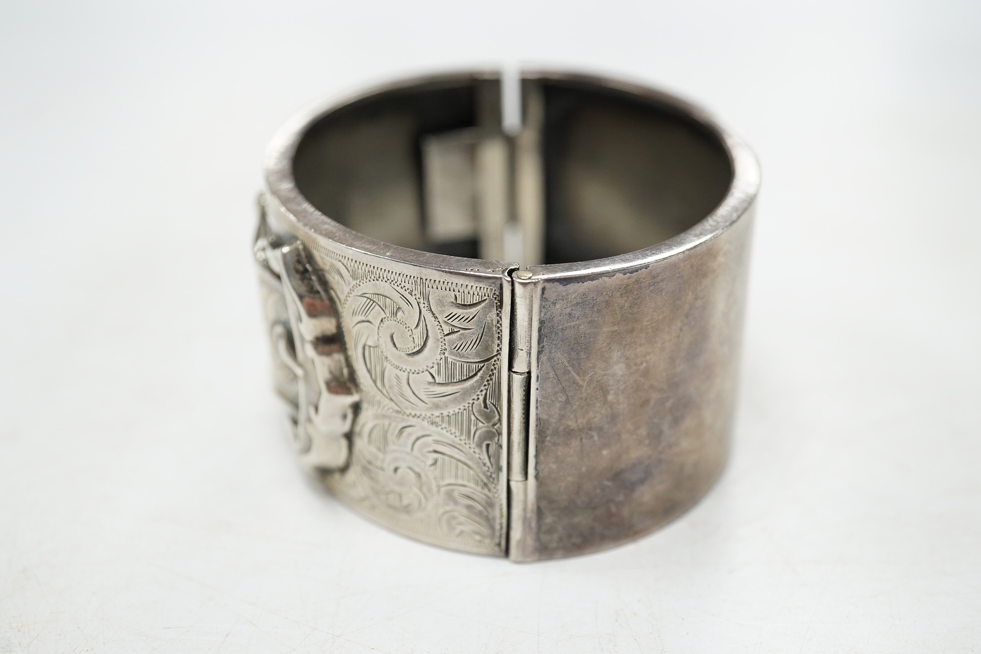 A George V engraved silver hinged bangle, with 'buckle' decoration, Kirwan & Co Ltd, Birmingham, 1913. Condition - poor to fair